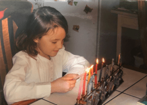 Alyssa, age 7 lights her family's menorah during Hanukkah